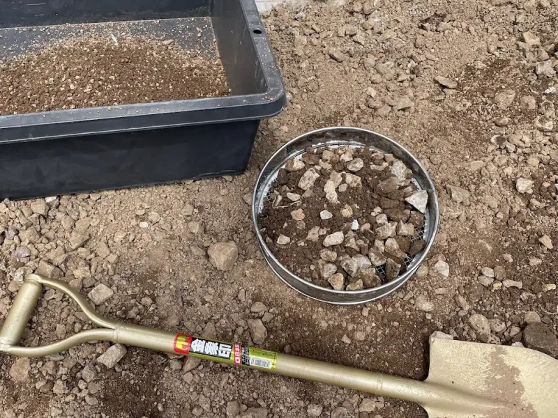 かたい土をふるいにかけている様子